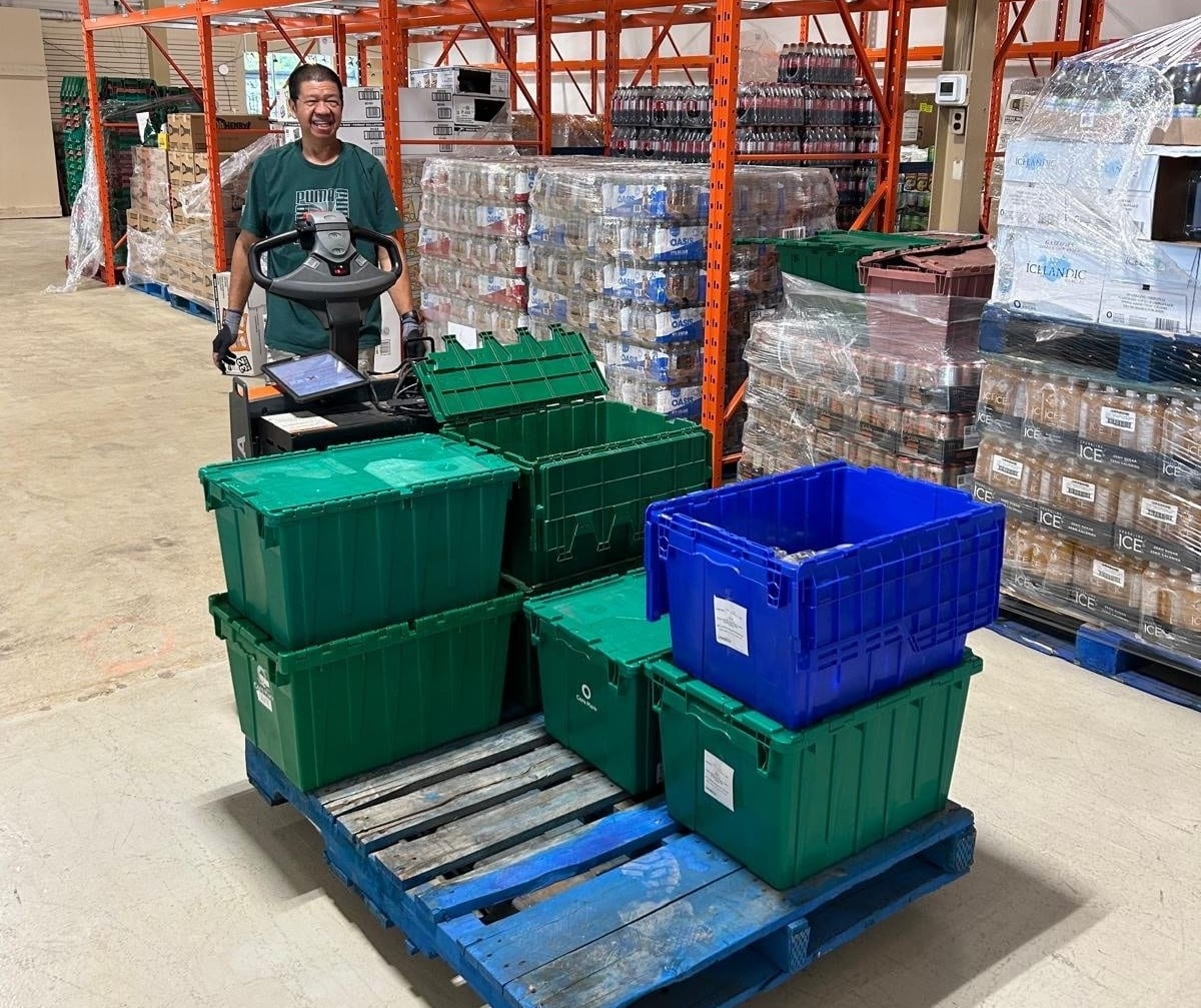 A Loyalty Markets employee with a cart to fill orders in a warehouse