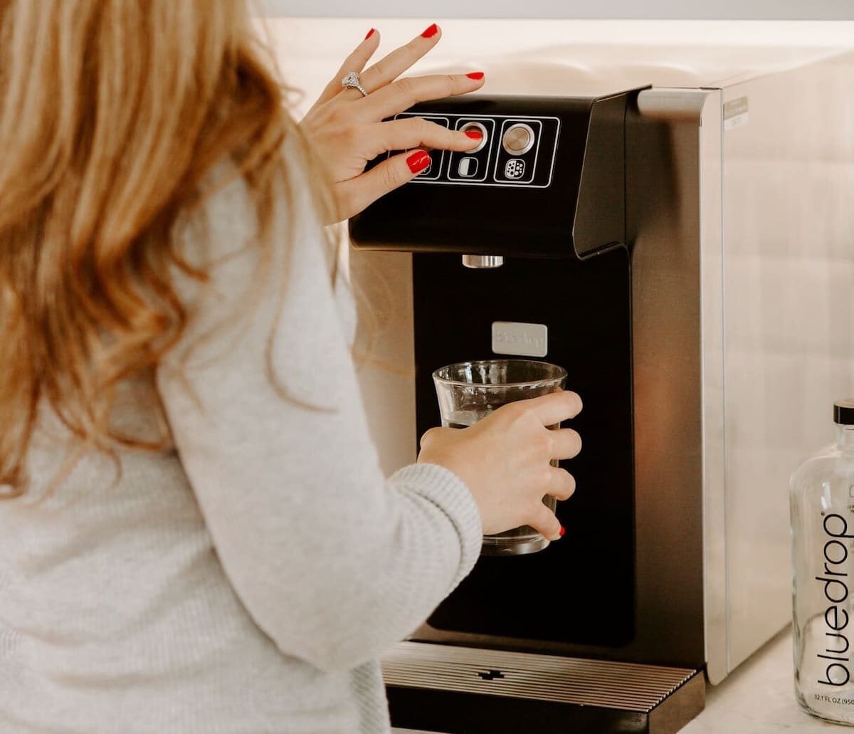 A person making a coffee using an environmentally friendly reusable cup