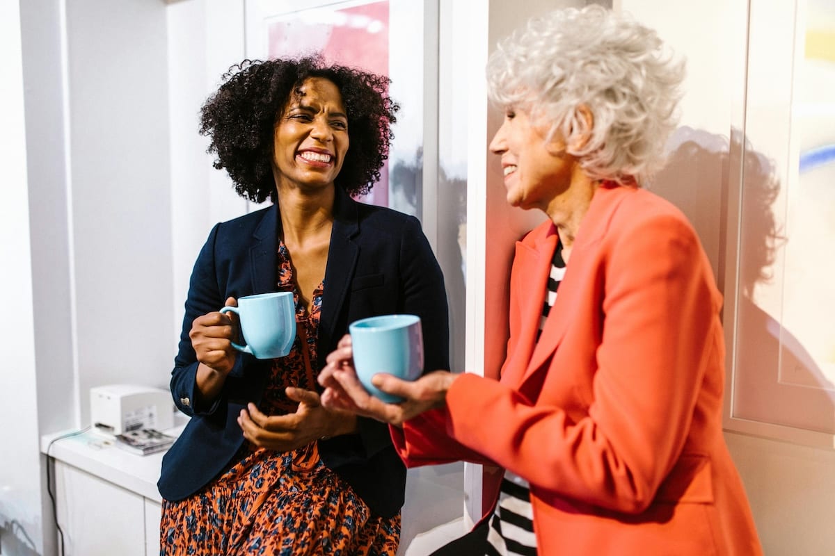 Two colleagues enjoying a memorable office experience over a cup of coffee