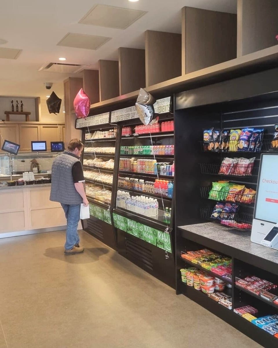 An employee at an integrated Loyalty Markets location with both unattended retail and a barista cafe